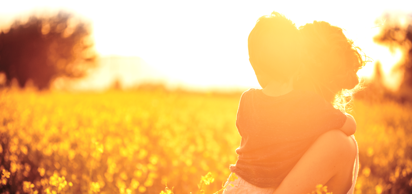 woman holding child looking to bright horizon